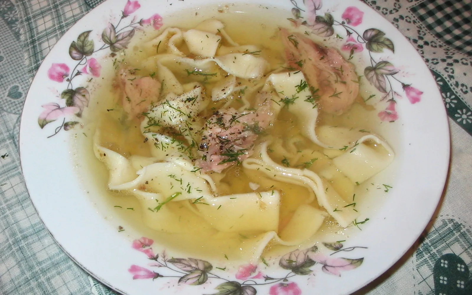A bowl of steaming noodle soup with vegetables and broth